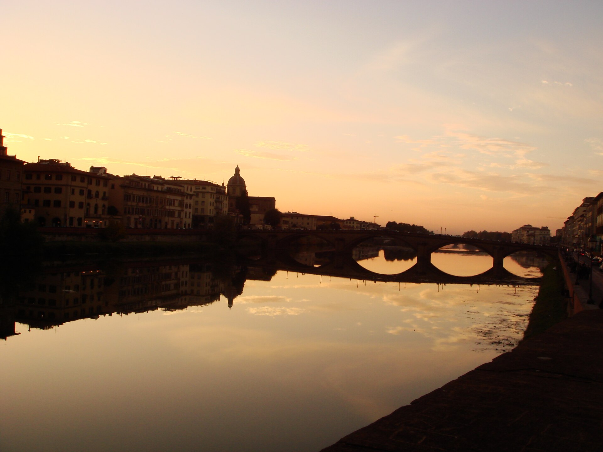 The Arno at sunset with the embankment and bridges in warm low light