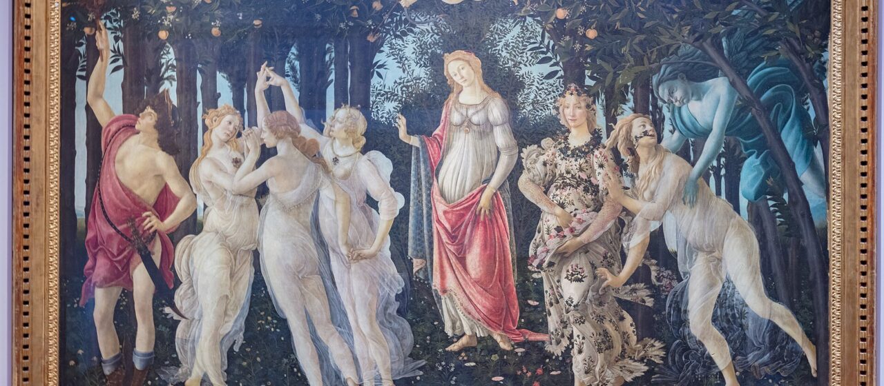 Botticelli's Primavera hanging in its gilt frame on a pale wall in the Uffizi Gallery