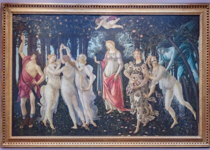 Botticelli's Primavera hanging in its gilt frame on a pale wall in the Uffizi Gallery