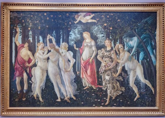 Botticelli's Primavera hanging in its gilt frame on a pale wall in the Uffizi Gallery