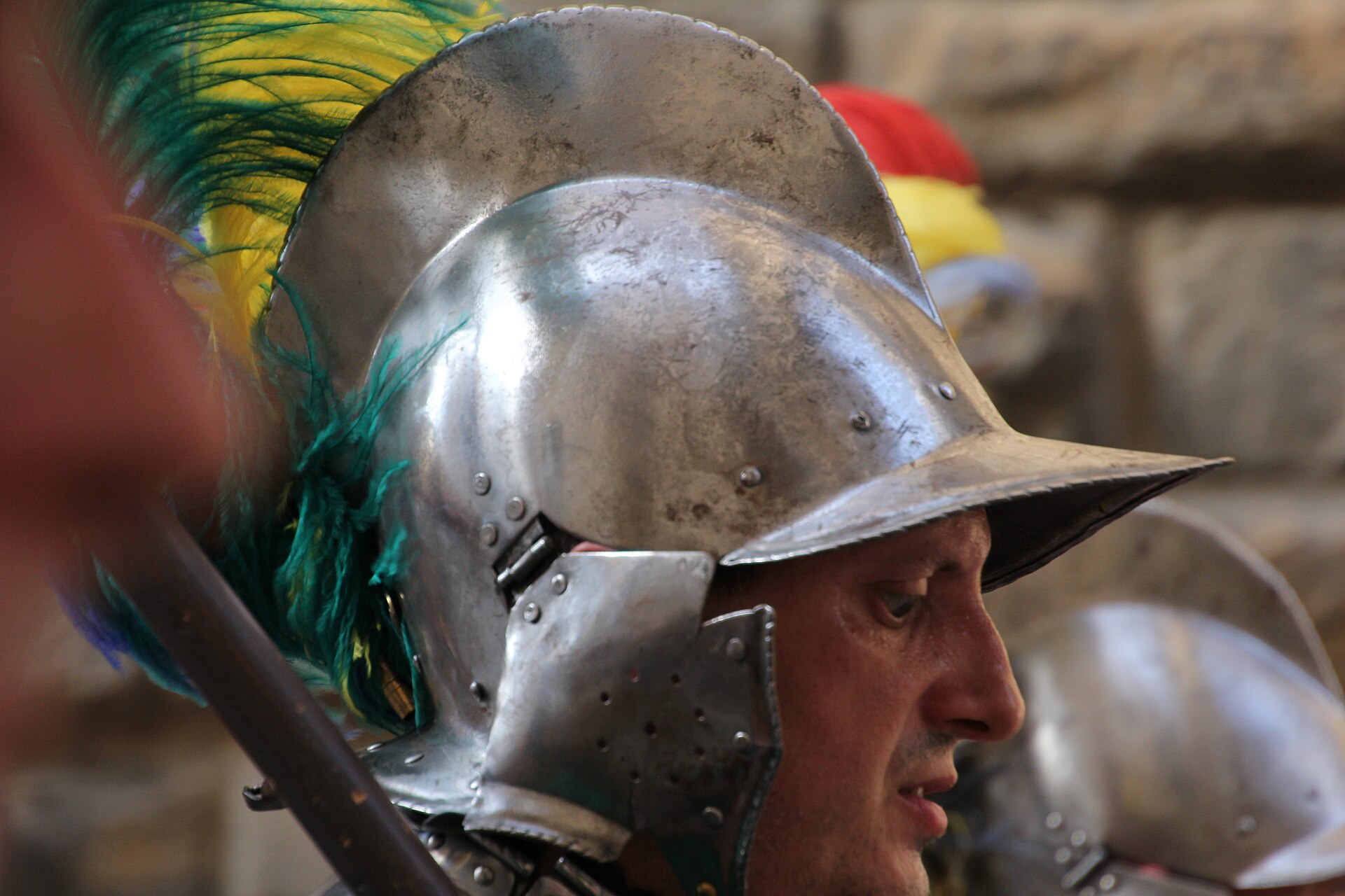 Close-up of a man in polished steel armour and a plumed helmet with green and yellow feathers, part of a Florentine historical procession