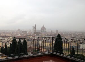 Florence seen through rain from the Villa Bardini terrace, the Duomo and Palazzo Vecchio tower half lost in grey murk above wet rooftops
