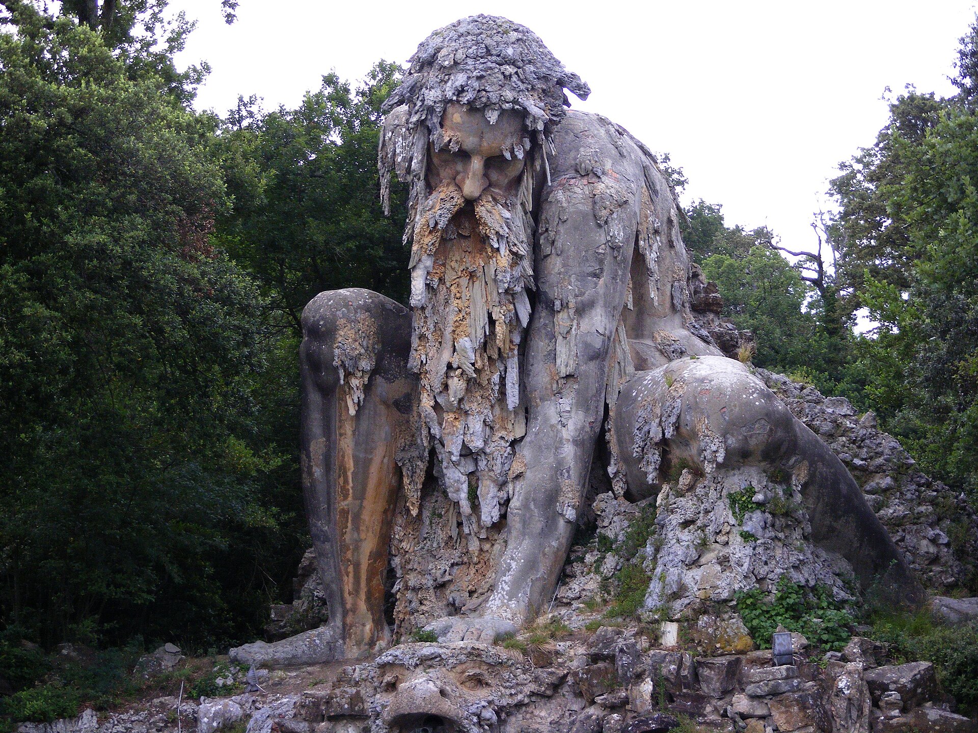 Giambologna's colossal Appennino statue at Pratolino, a crouching bearded stone giant encrusted with rock formations, set among trees
