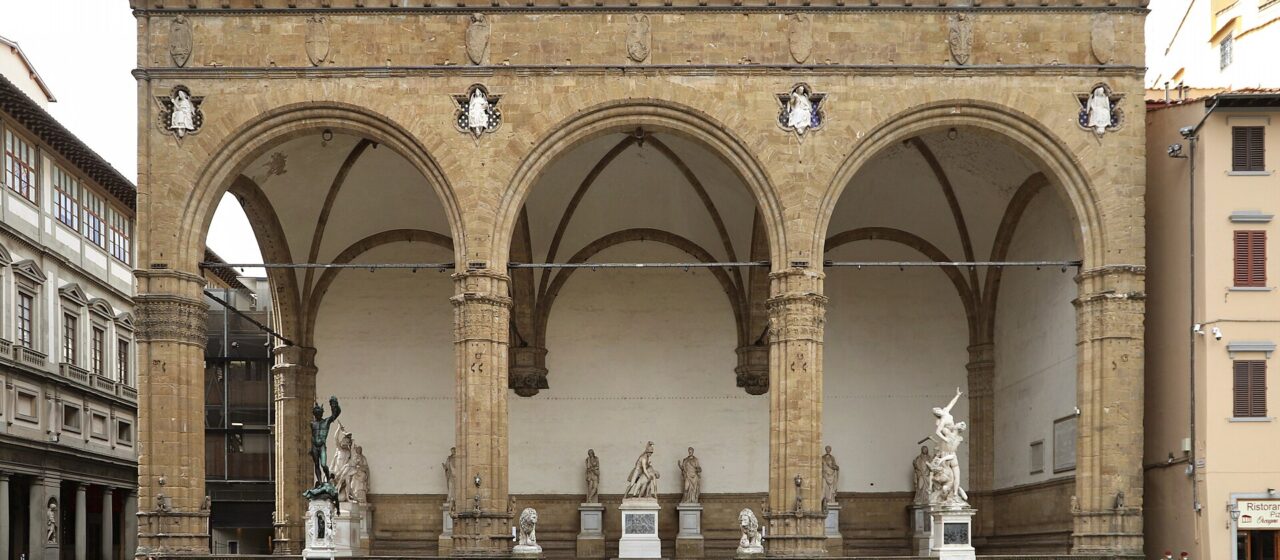 The three tall Gothic arches of the Loggia dei Lanzi in Florence sheltering Renaissance marble and bronze sculptures