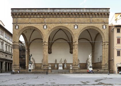 The three tall Gothic arches of the Loggia dei Lanzi in Florence sheltering Renaissance marble and bronze sculptures