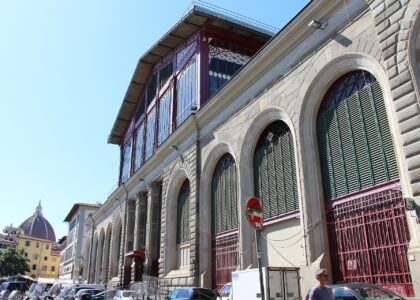 The stone and cast-iron exterior of the Mercato Centrale in Florence with the Duomo visible in the distance