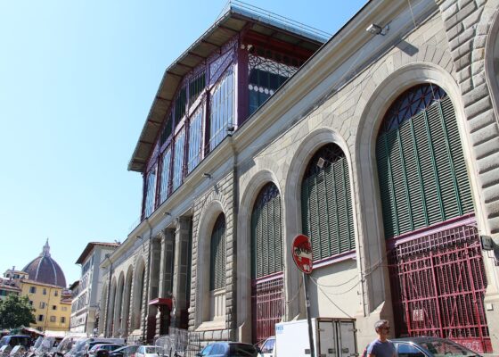 The stone and cast-iron exterior of the Mercato Centrale in Florence with the Duomo visible in the distance