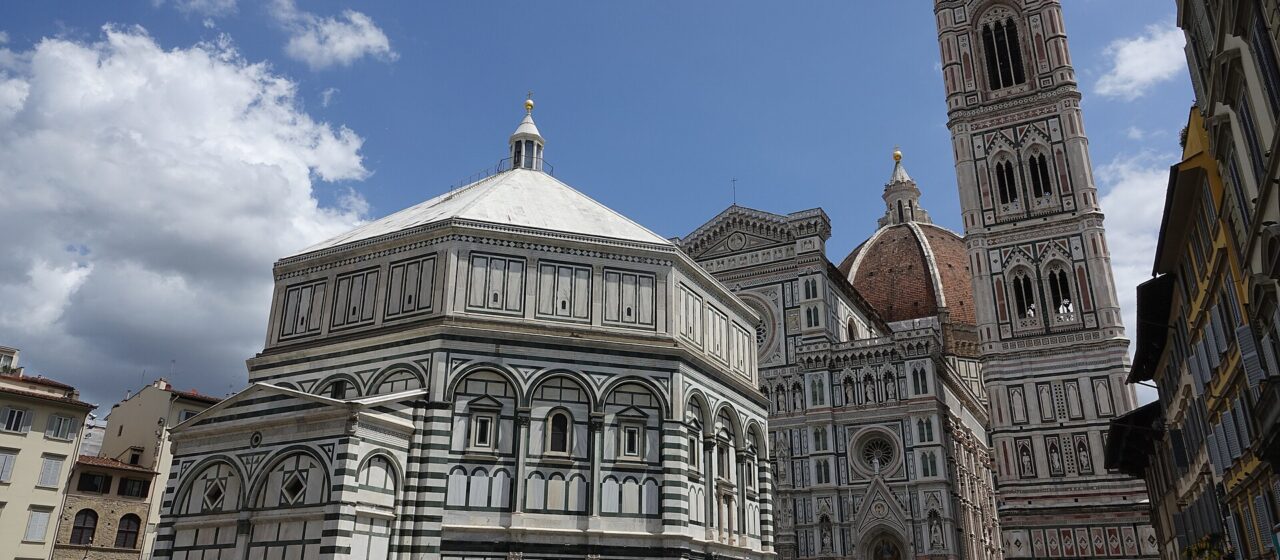 Crowds in Piazza del Duomo in Florence in summer with the Baptistery, cathedral facade and bell tower behind