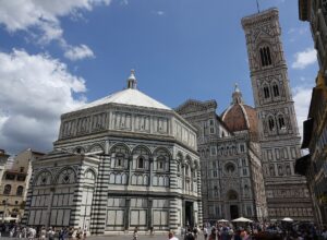Crowds in Piazza del Duomo in Florence in summer with the Baptistery, cathedral facade and bell tower behind