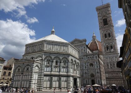 Crowds in Piazza del Duomo in Florence in summer with the Baptistery, cathedral facade and bell tower behind