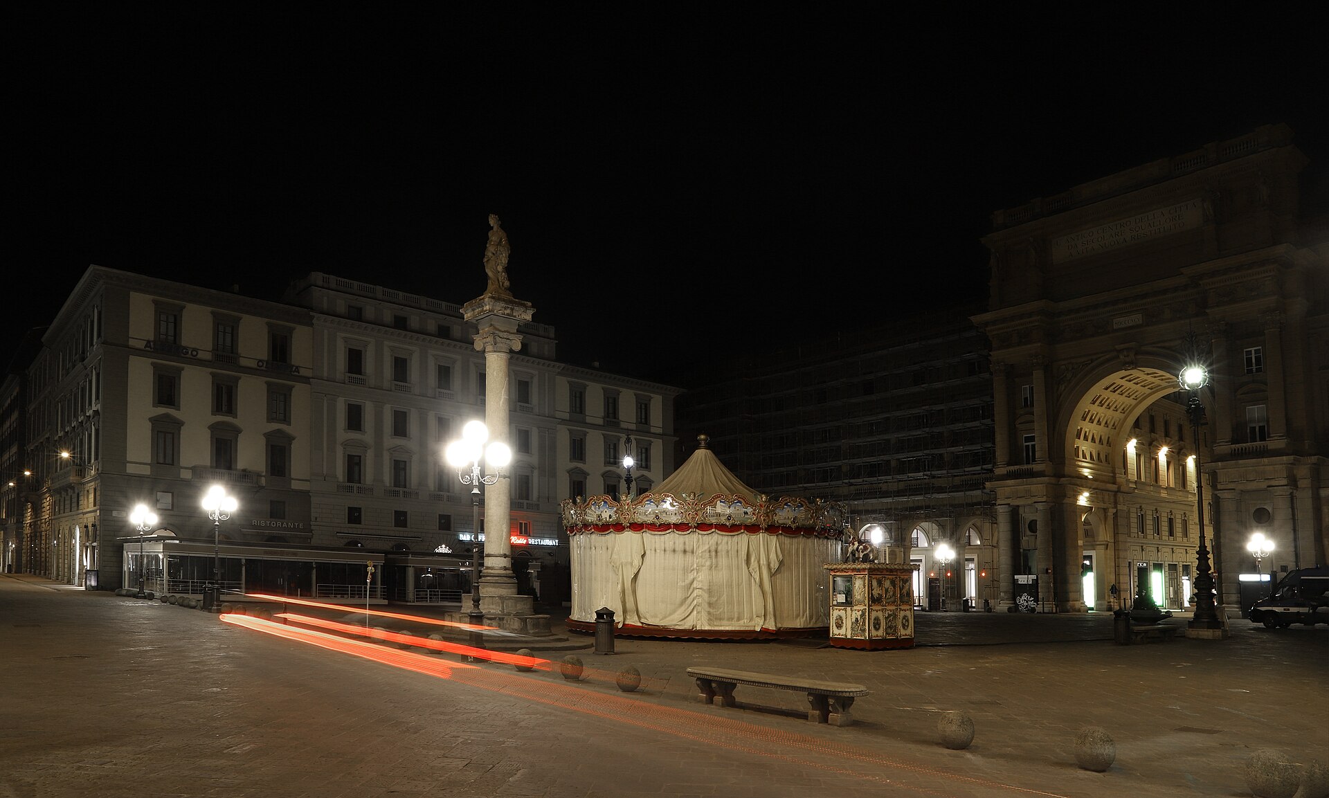 Piazza della Repubblica at night, empty, the historic carousel covered by its canvas cover under street lamps