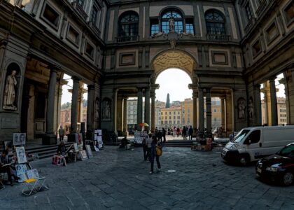 The long colonnaded courtyard of the Uffizi looking towards the arch that frames the Arno, with street artists and their easels along one side