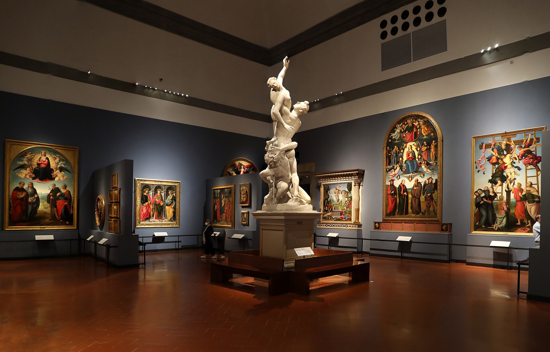 The Sala del Colosso in Florence's Accademia Gallery, with Giambologna's plaster model for the Rape of the Sabines at the centre and Renaissance altarpieces on blue walls
