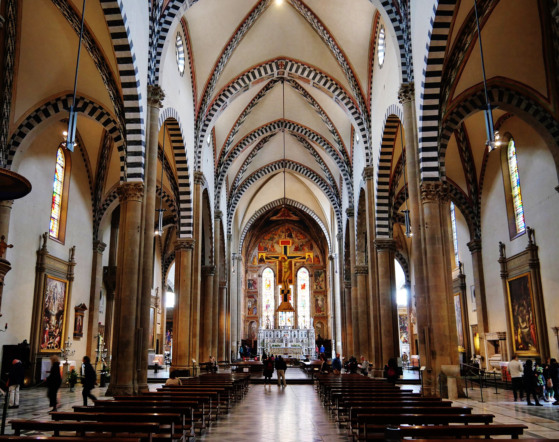 The striped Gothic nave of Santa Maria Novella in Florence looking towards the crucifix and the frescoed apse
