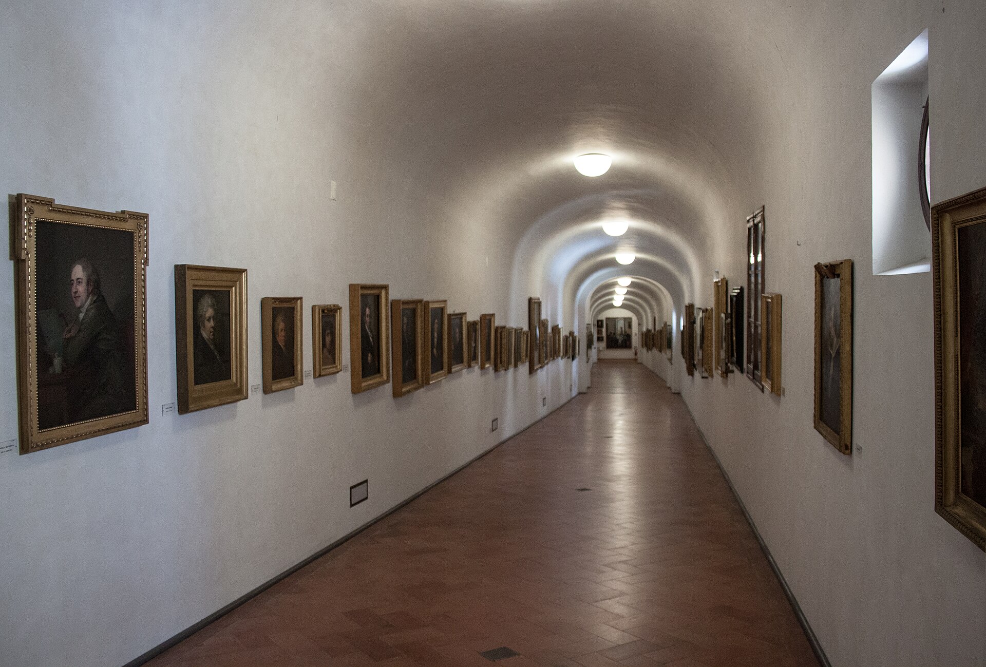 The long vaulted interior of the Vasari Corridor lined with framed portrait paintings, photographed before its closure