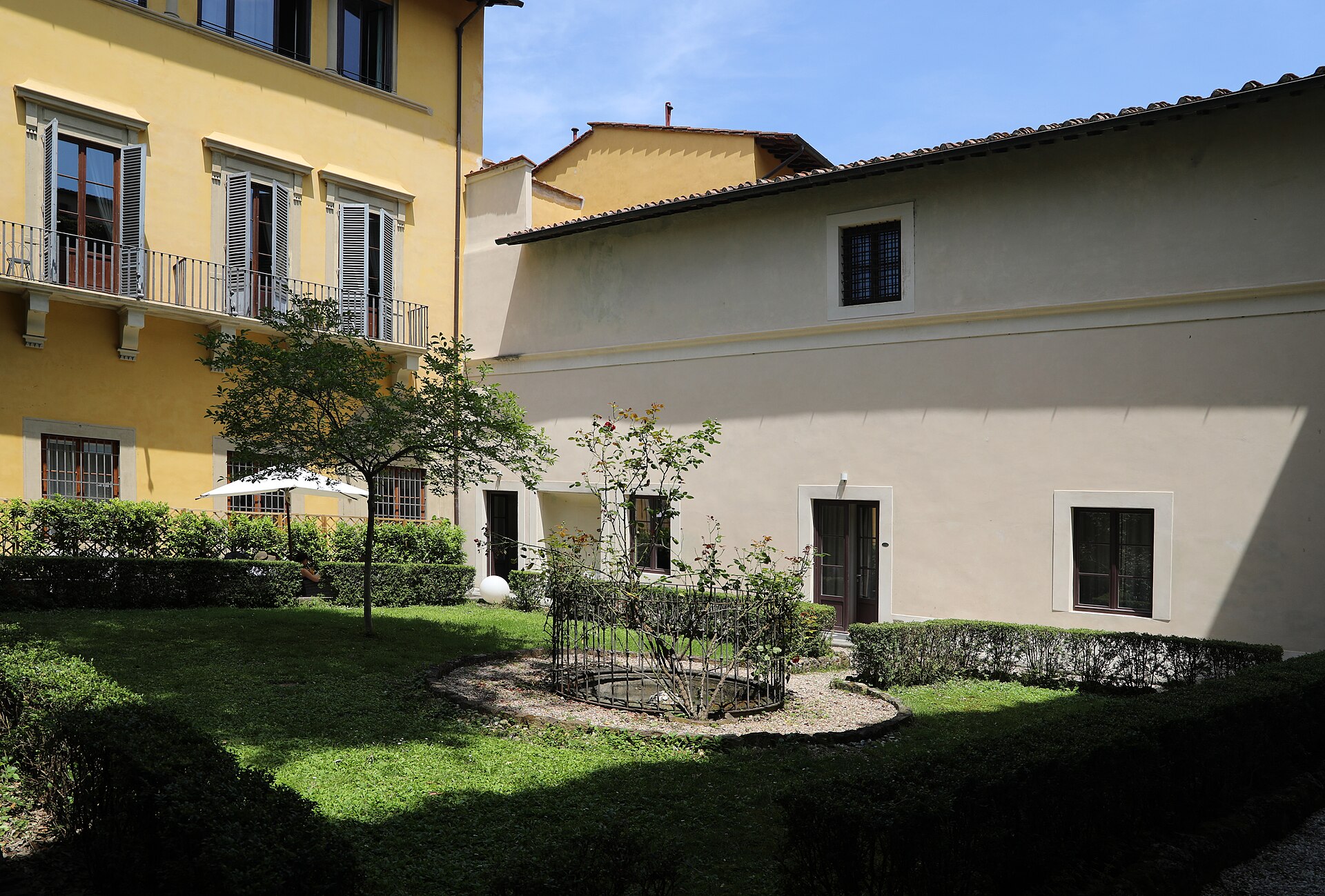 A private walled garden in the Florence Oltrarno with the plain low wall of the Vasari Corridor running along one side