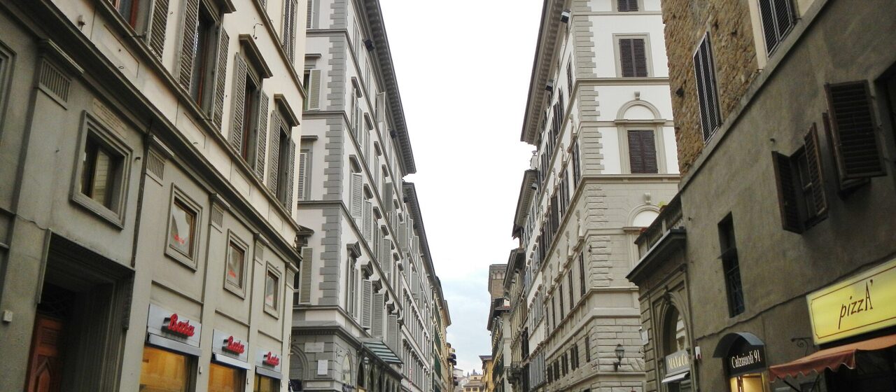 Via dei Calzaiuoli in Florence filled with pedestrians walking between shop fronts with no traffic