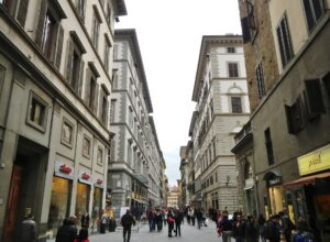 Via dei Calzaiuoli in Florence filled with pedestrians walking between shop fronts with no traffic
