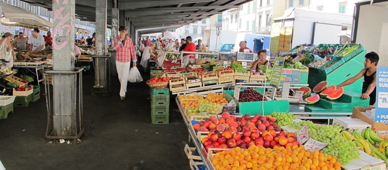 Apricots, peaches, grapes and watermelon fill fruit displays beneath the covered arcade at Florence's Sant'Ambrogio market.