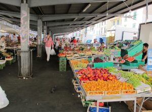 Apricots, peaches, grapes and watermelon fill fruit displays beneath the covered arcade at Florence's Sant'Ambrogio market.