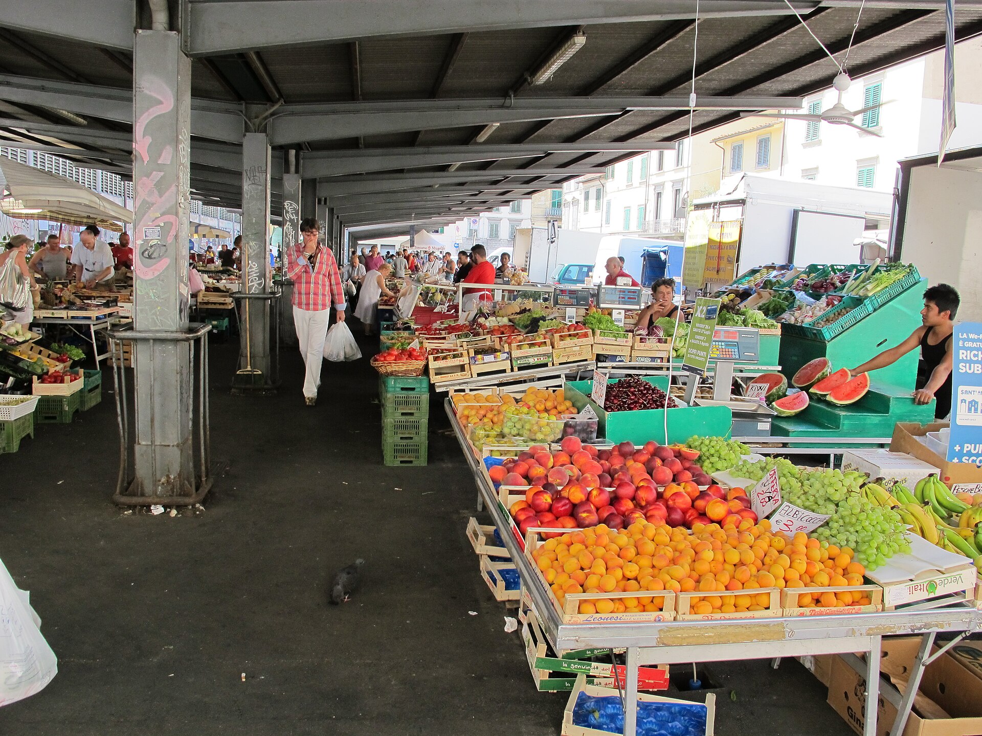 Apricots, peaches, grapes and watermelon fill fruit displays beneath the covered arcade at Florence's Sant'Ambrogio market.