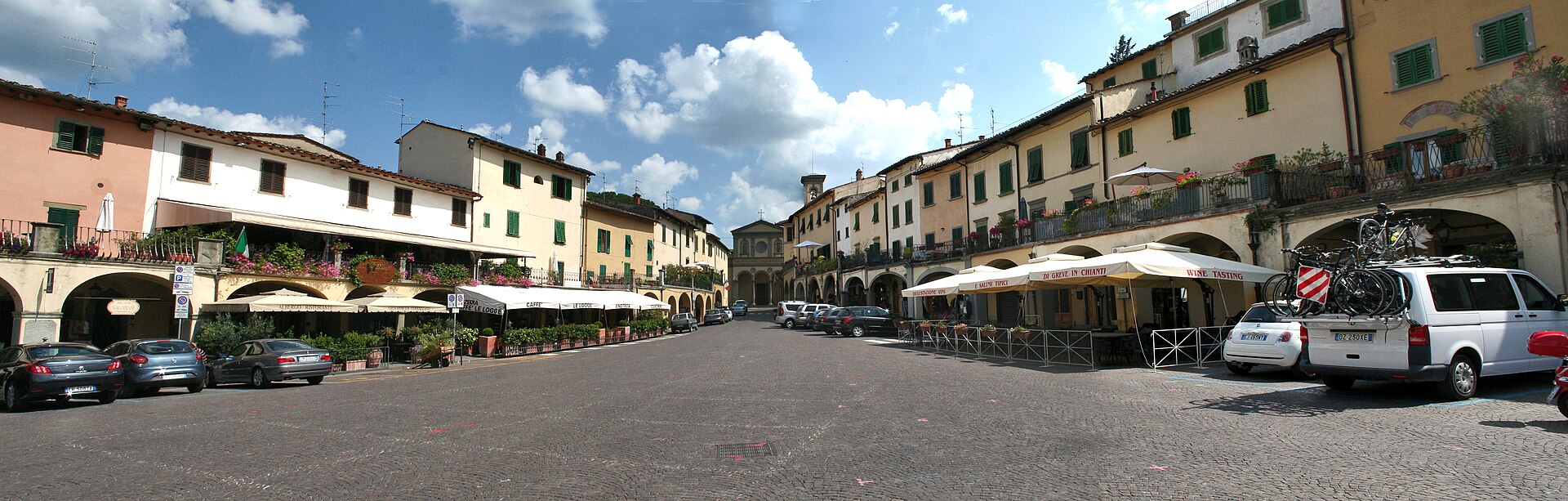 Arcaded buildings and cafe awnings line Greve in Chianti’s broad Piazza Matteotti, which narrows towards the distant street.