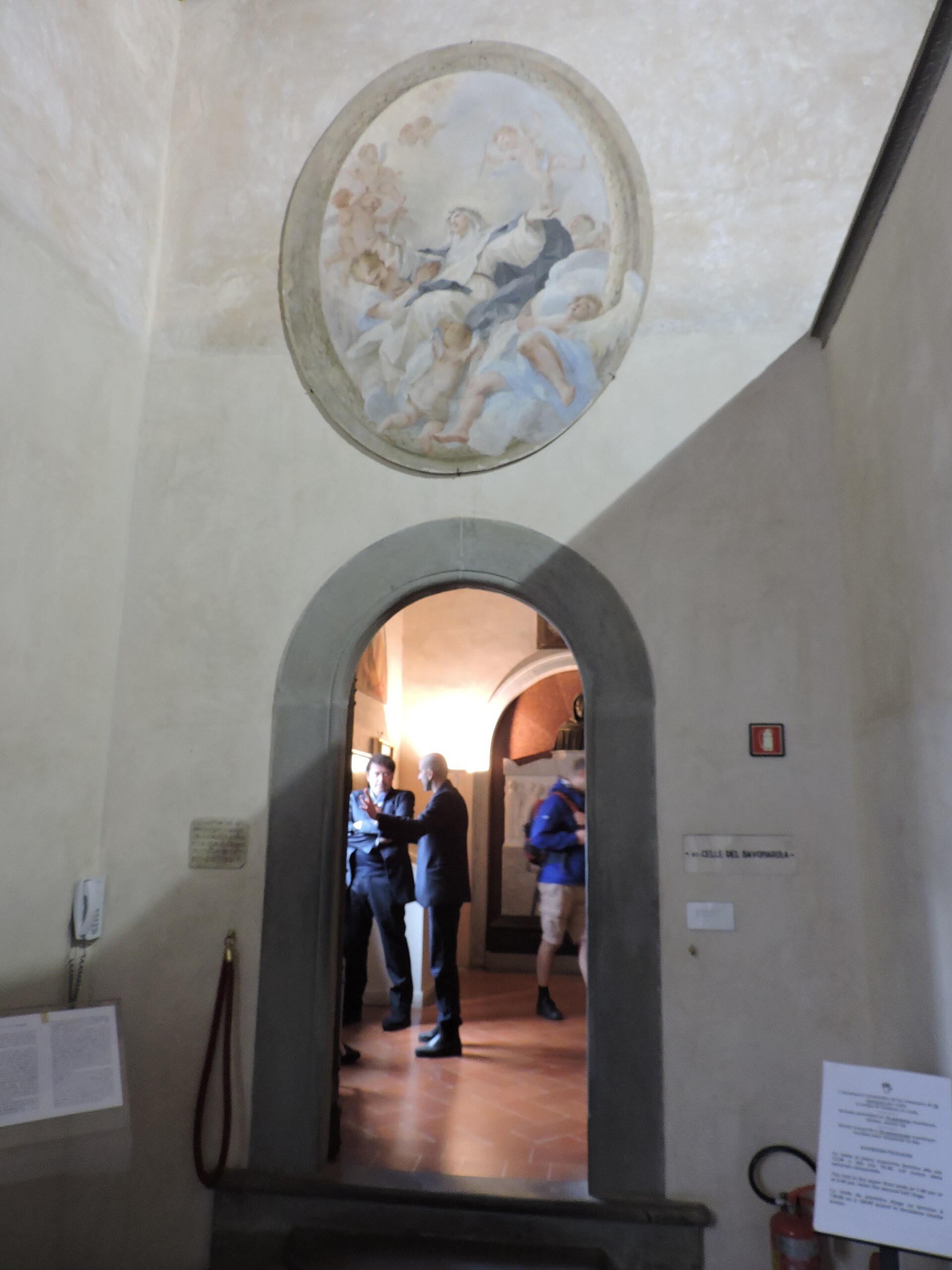 An arched doorway leads into Savonarola's quarters at Florence's San Marco museum, beneath an oval religious fresco.