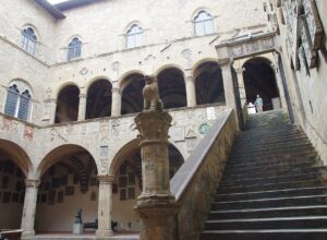 The Bargello courtyard in Florence has a broad outdoor staircase, two levels of arches and carved coats of arms.