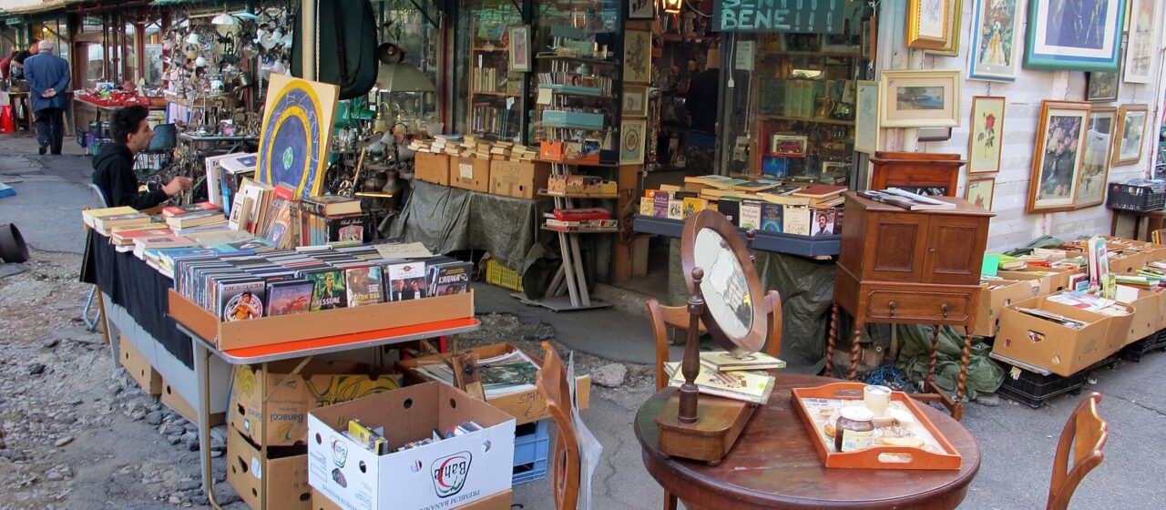 Books, framed pictures, mirrors and wooden furniture fill a covered stall at Florence's Mercato delle Pulci in Piazza dei Ciompi.