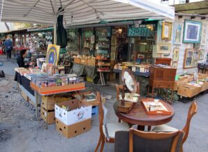 Books, framed pictures, mirrors and wooden furniture fill a covered stall at Florence's Mercato delle Pulci in Piazza dei Ciompi.