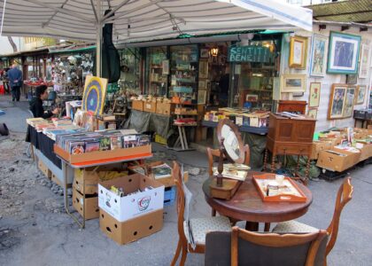 Books, framed pictures, mirrors and wooden furniture fill a covered stall at Florence's Mercato delle Pulci in Piazza dei Ciompi.