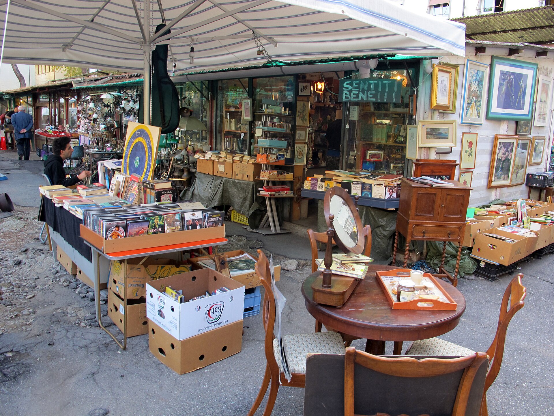Books, framed pictures, mirrors and wooden furniture fill a covered stall at Florence's Mercato delle Pulci in Piazza dei Ciompi.
