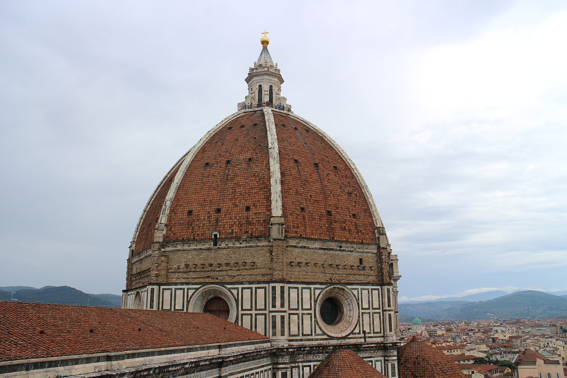Brunelleschi's terracotta dome and white marble ribs fill the view from Giotto's bell tower, with Florence rooftops and hills beyond.