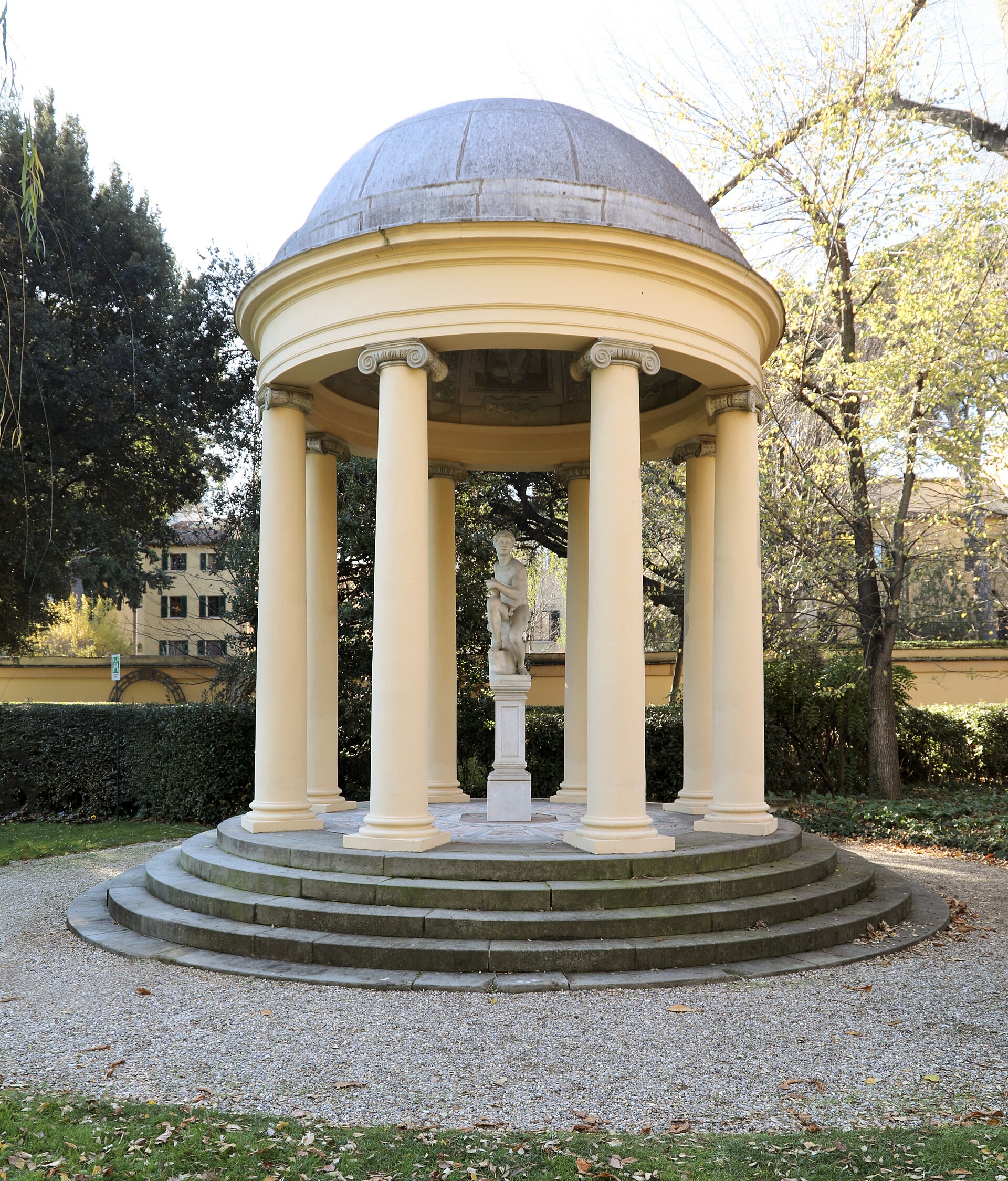 A circular columned pavilion shelters a statue among trees in the garden of Palazzo della Gherardesca, Florence.