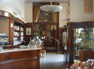 A curved wood-and-marble counter, espresso machine, bottles and glassware fill the historic interior of Caffe Paszkowski in Florence.