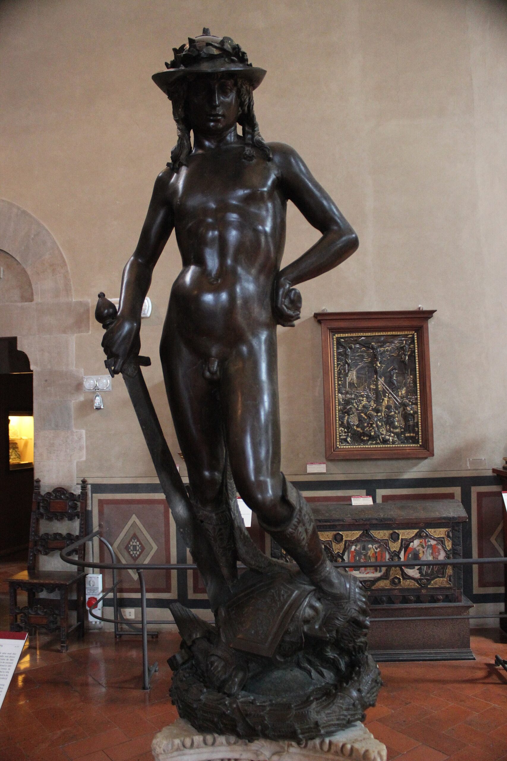 Donatello's bronze David wears a hat and holds a sword above Goliath's head in Florence's Bargello museum.