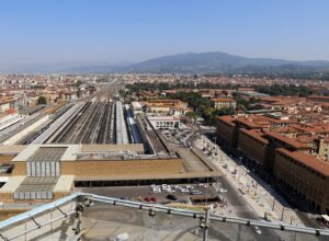 Florence Santa Maria Novella station seen from above, with its stone facade, taxi forecourt and long platform roofs.