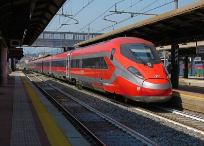 A red Frecciarossa 1000 high-speed train with a silver nose standing at a platform in Florence under a station canopy