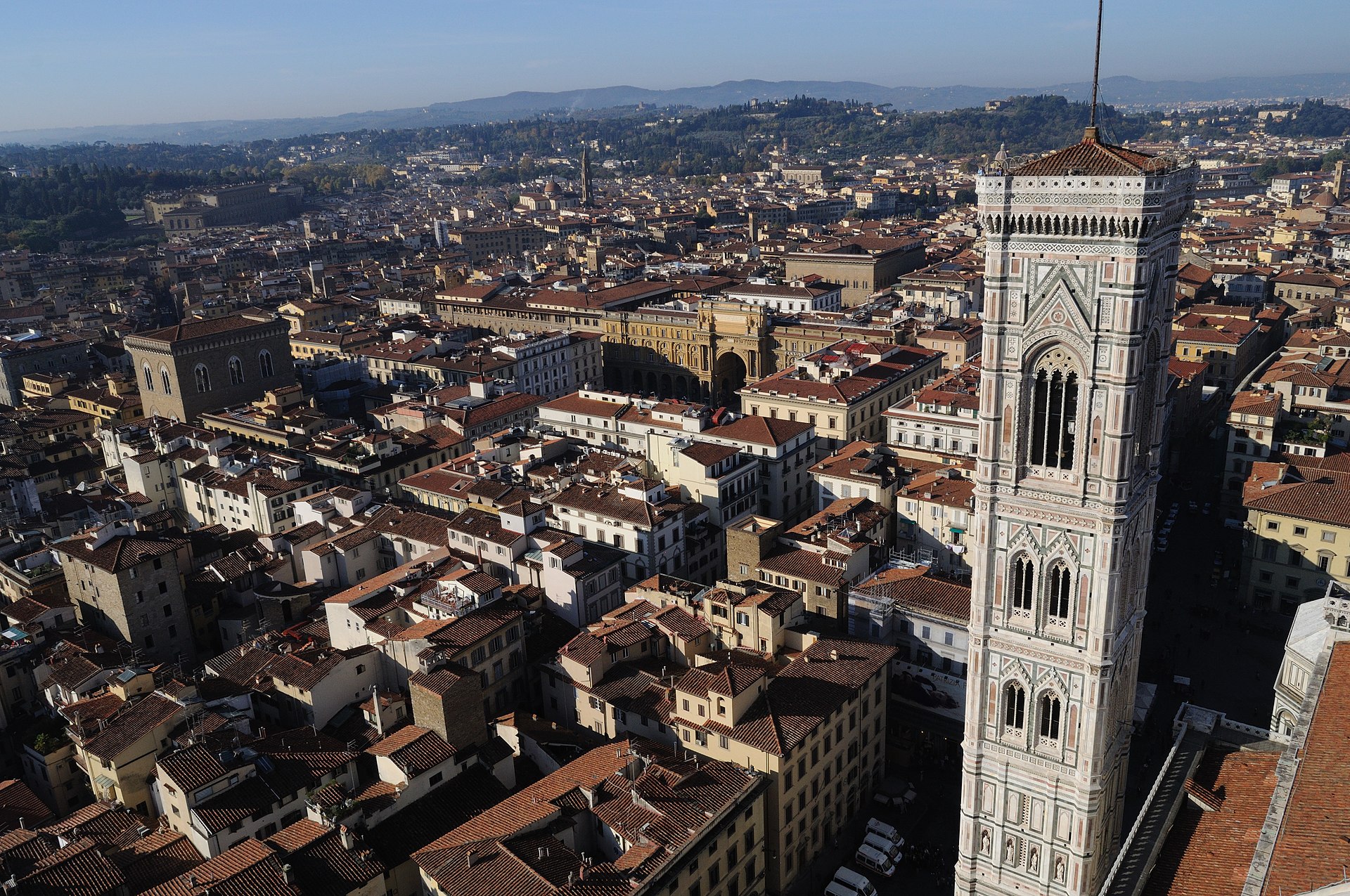 Giotto's marble bell tower rises below the dome viewpoint above Florence's red rooftops, with Palazzo Vecchio and distant hills beyond.