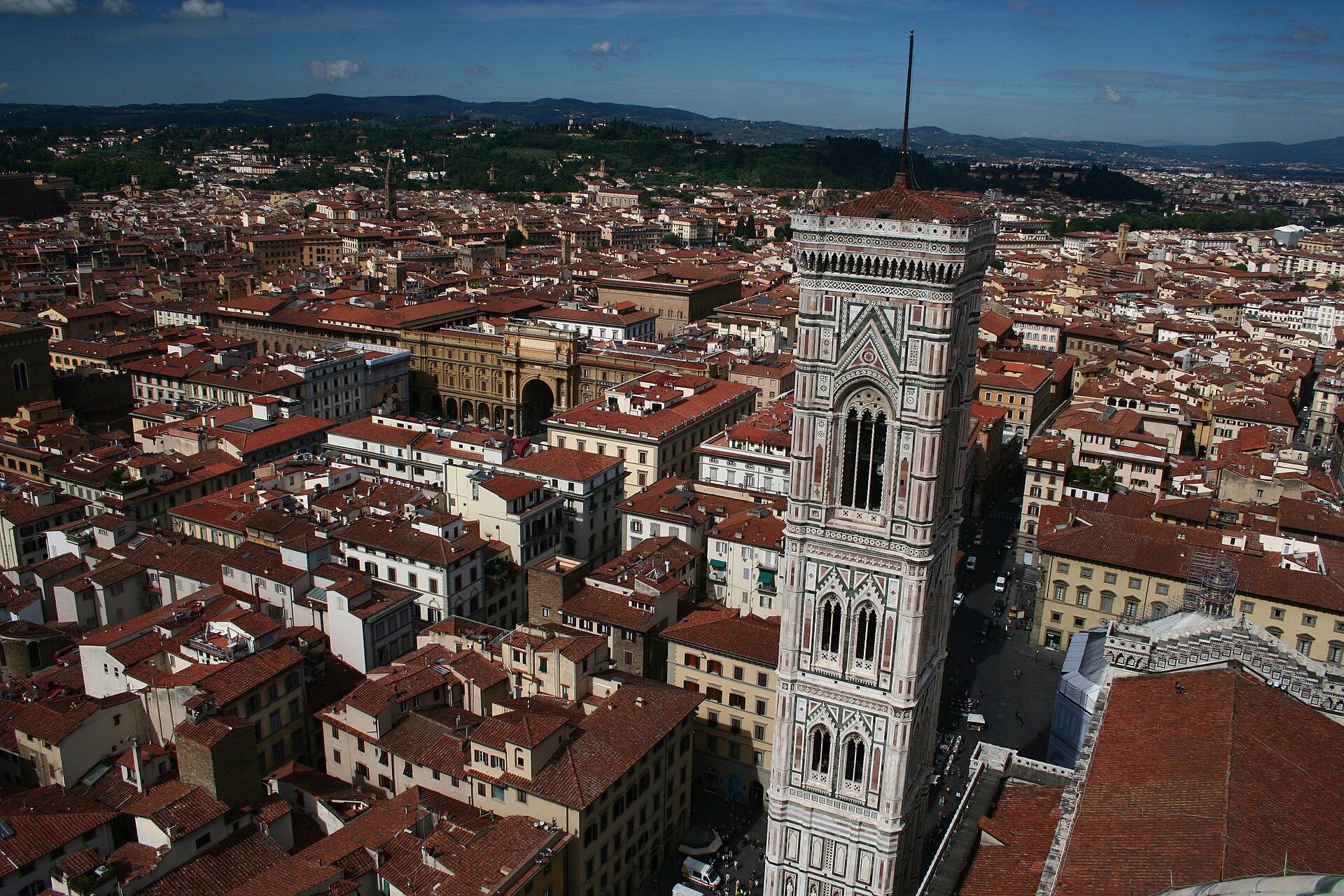 Giotto's patterned marble campanile stands below the cathedral dome viewpoint, surrounded by Florence's tiled rooftops and hills in the distance.