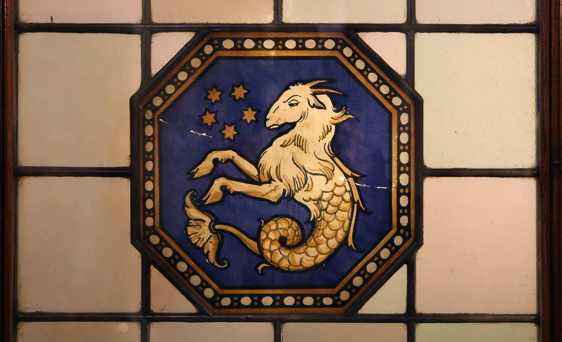 A golden goat with a curling fish tail decorates a blue stained-glass panel inside Florence’s Hotel Porta Rossa.