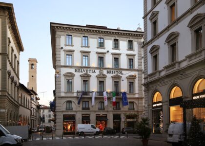 Helvetia and Bristol’s pale palazzo facade rises above a Florence street, with hotel lettering and flags across its balcony.
