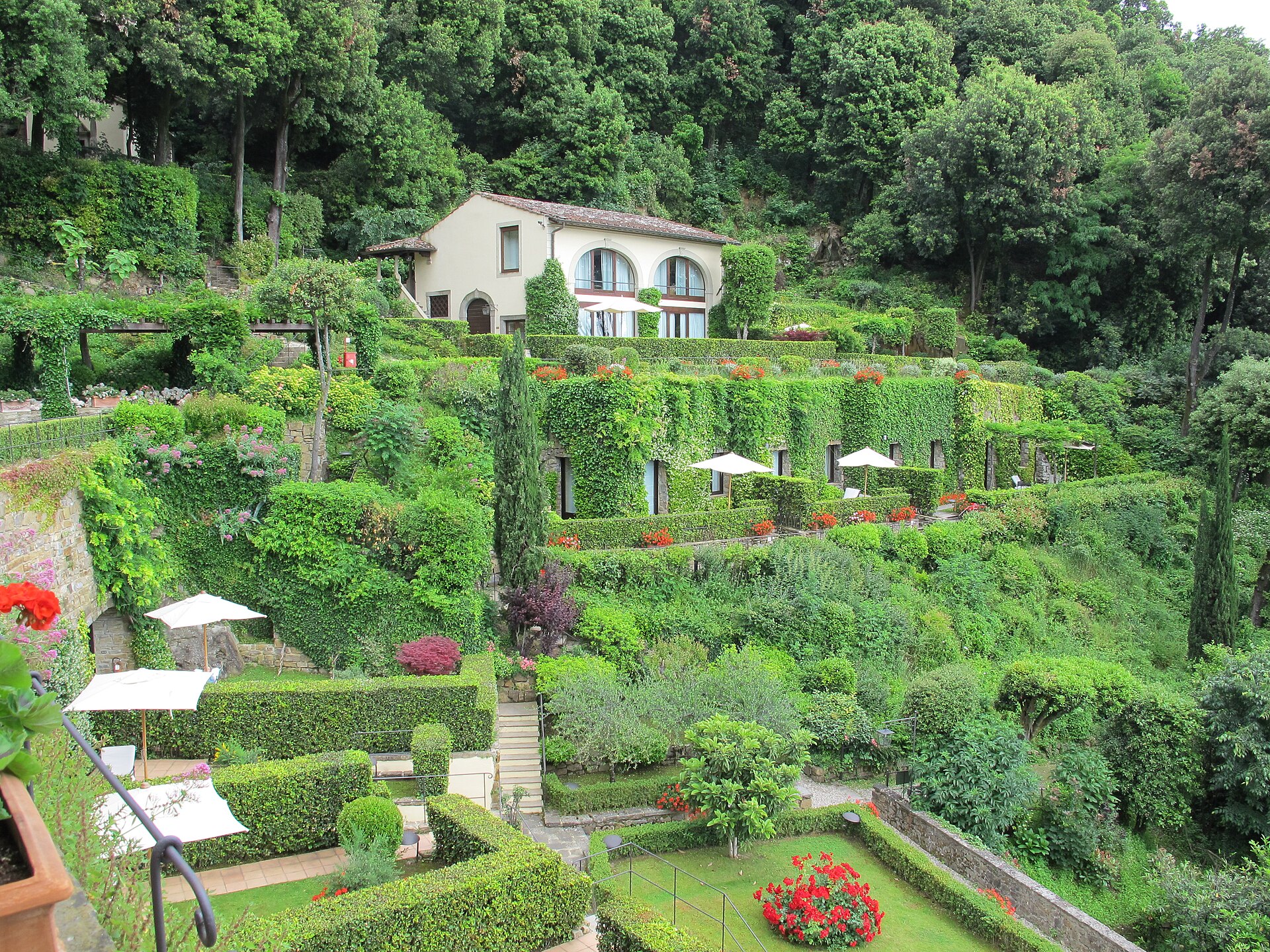 Ivy-covered terraces, clipped hedges and cypresses surround a pale building at Villa San Michele in Fiesole.