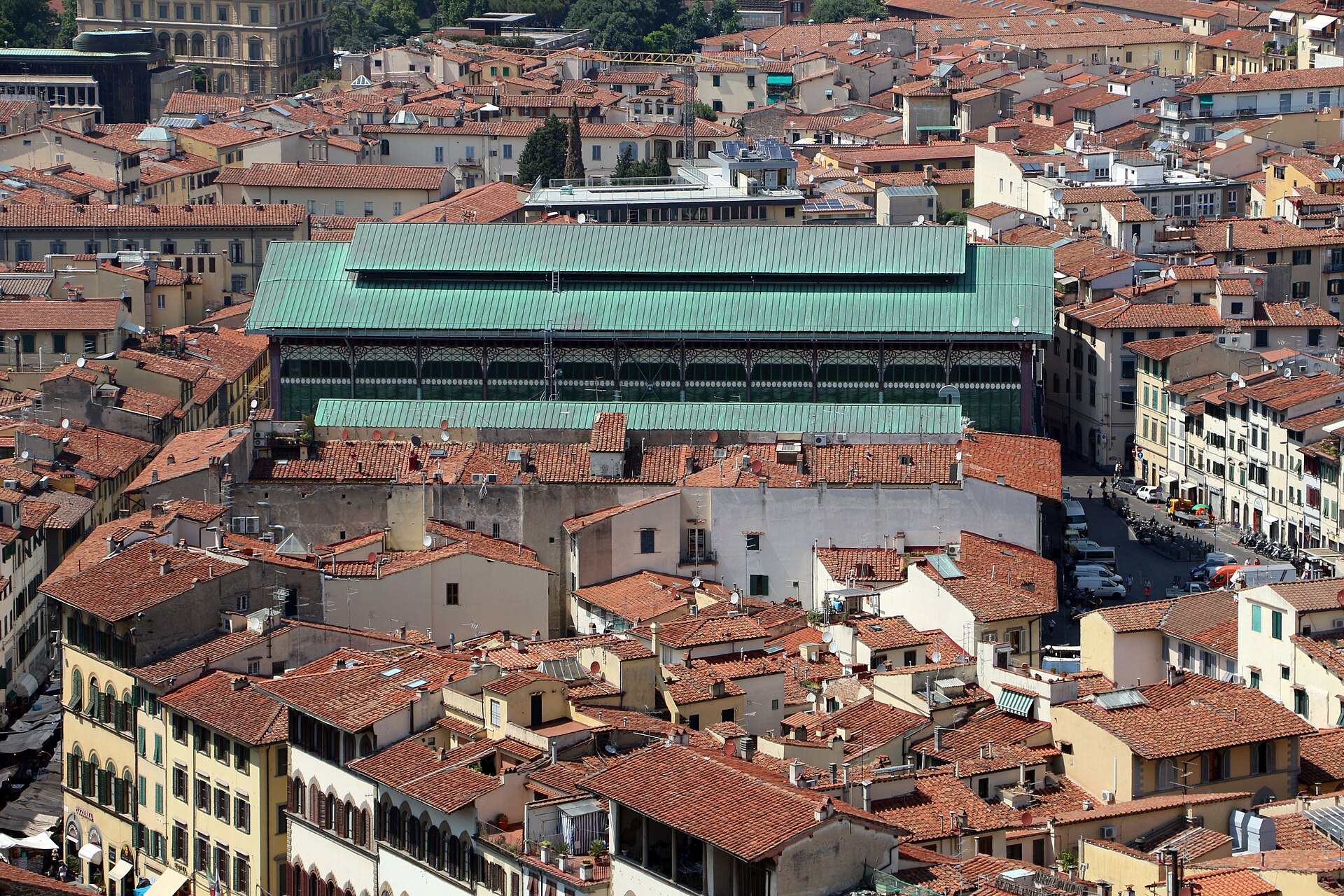Mercato Centrale's long green roof rises above red-tiled buildings in an elevated view over central Florence.