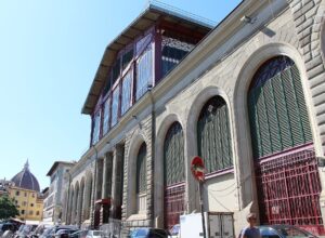 Mercato Centrale's stone arches, green shutters and red iron upper structure line a sunny street in central Florence.