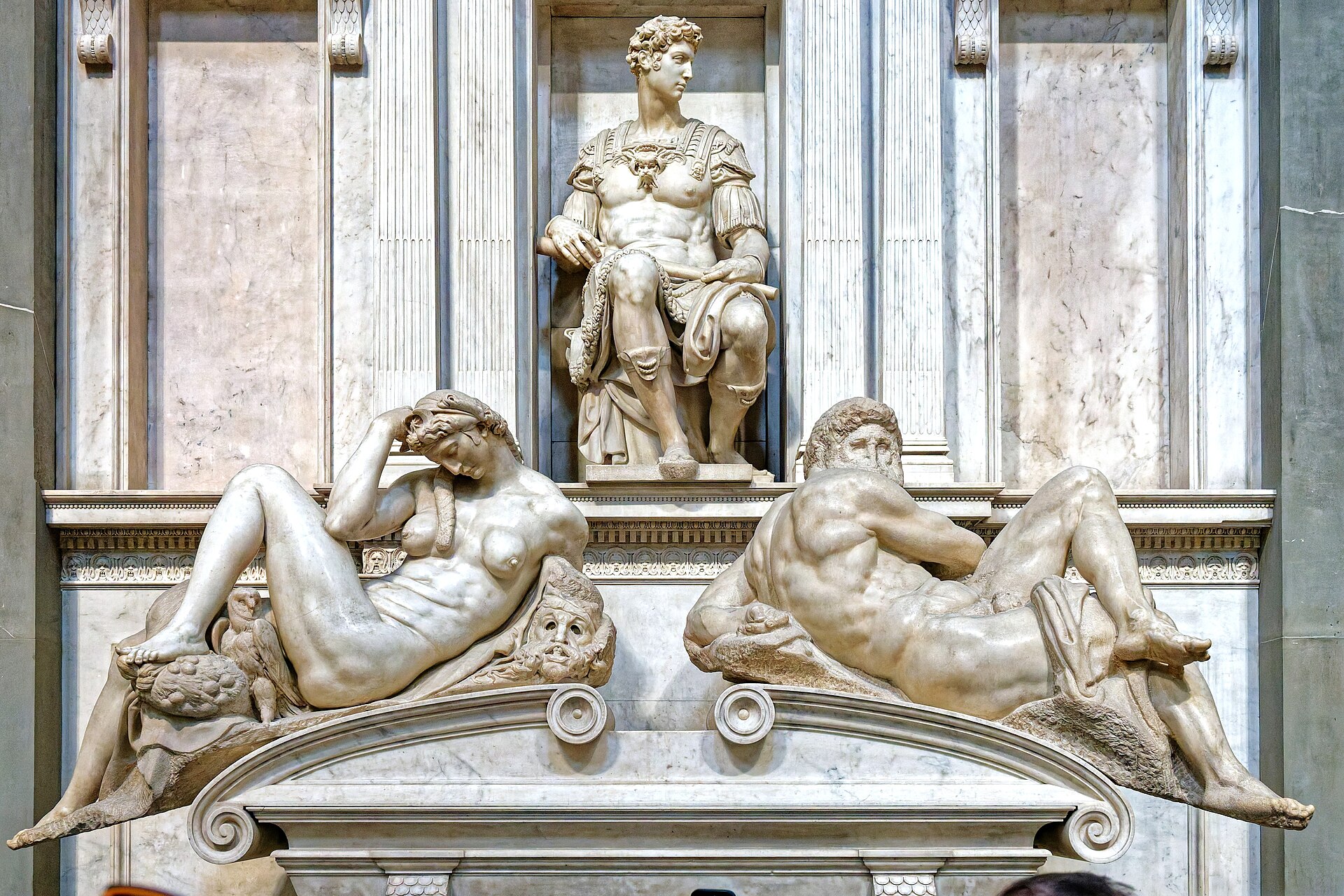 Michelangelo's reclining Night and Day flank the curved sarcophagus beneath Giuliano de' Medici in Florence's New Sacristy.