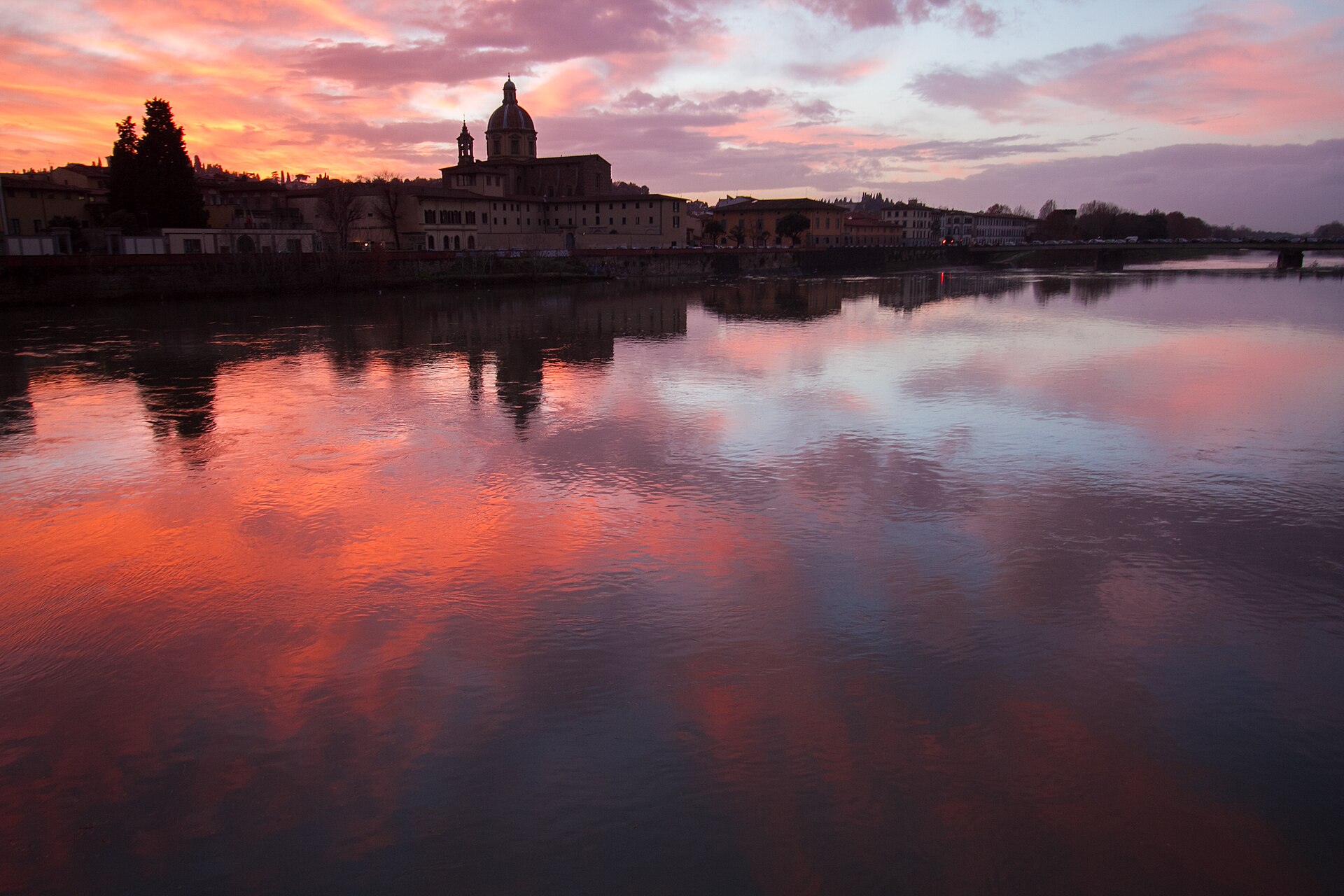 Orange and pink December clouds reflect across the Arno beside San Frediano in Cestello and Florence’s riverfront buildings.