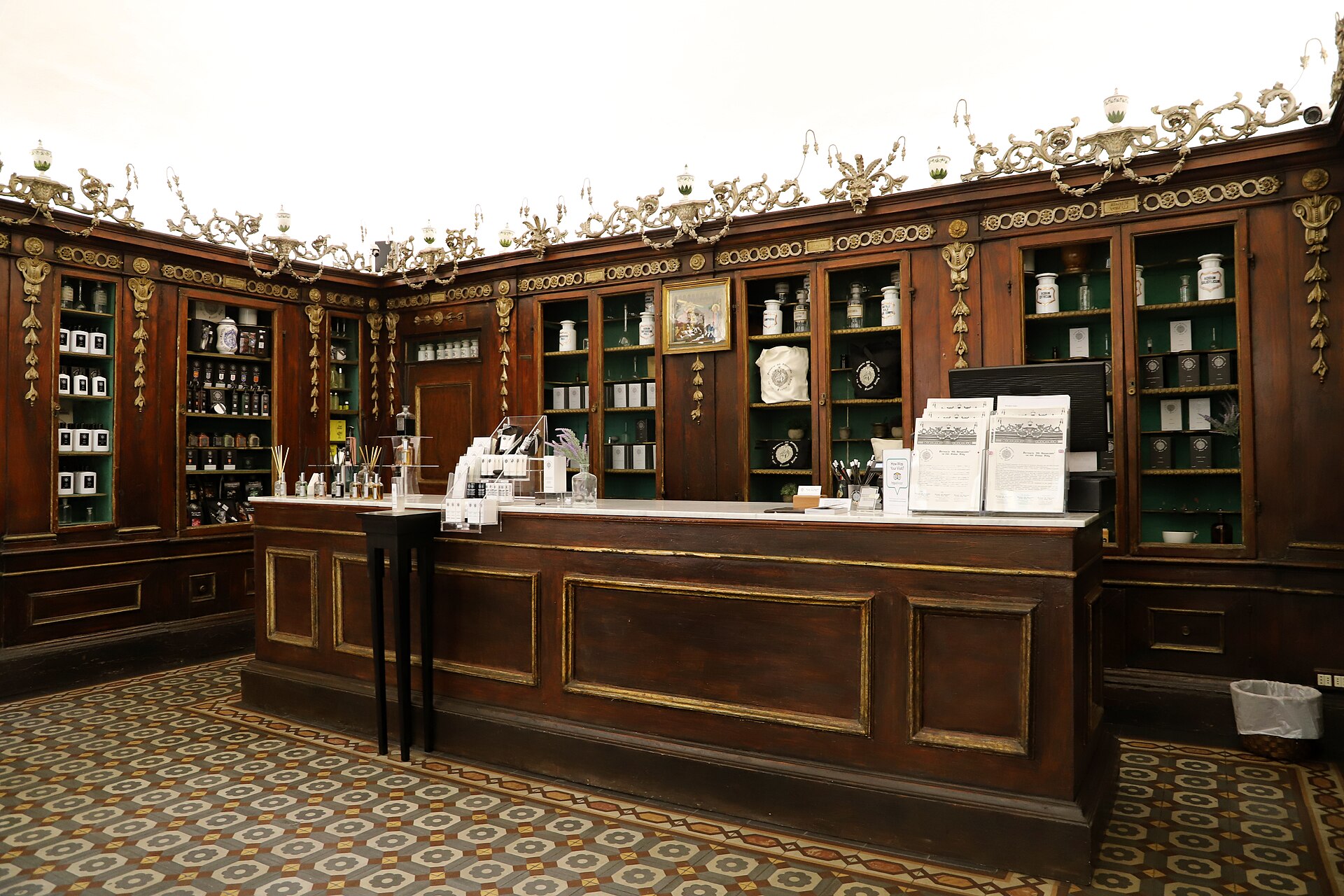 Ornate wooden cabinets and rows of jars surround the counter inside Florence's historic Farmacia della Santissima Annunziata.