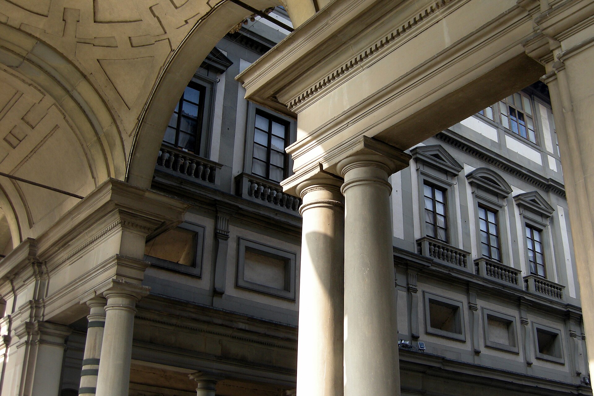 Paired columns and a coffered arch frame the opposite facade of the Uffizi courtyard in Florence.