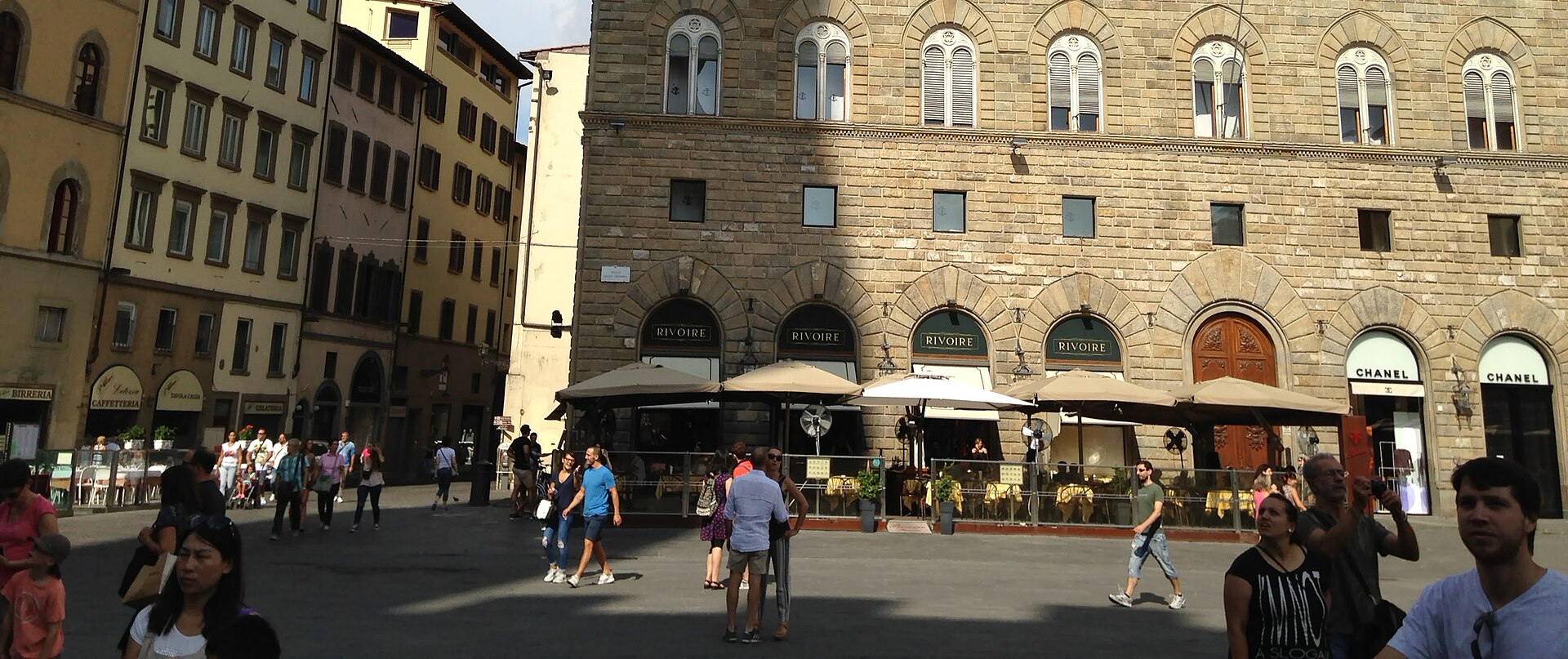 Patrons sit beneath Rivoire’s awnings on Florence’s Piazza della Signoria while pedestrians pass across the paving in front.